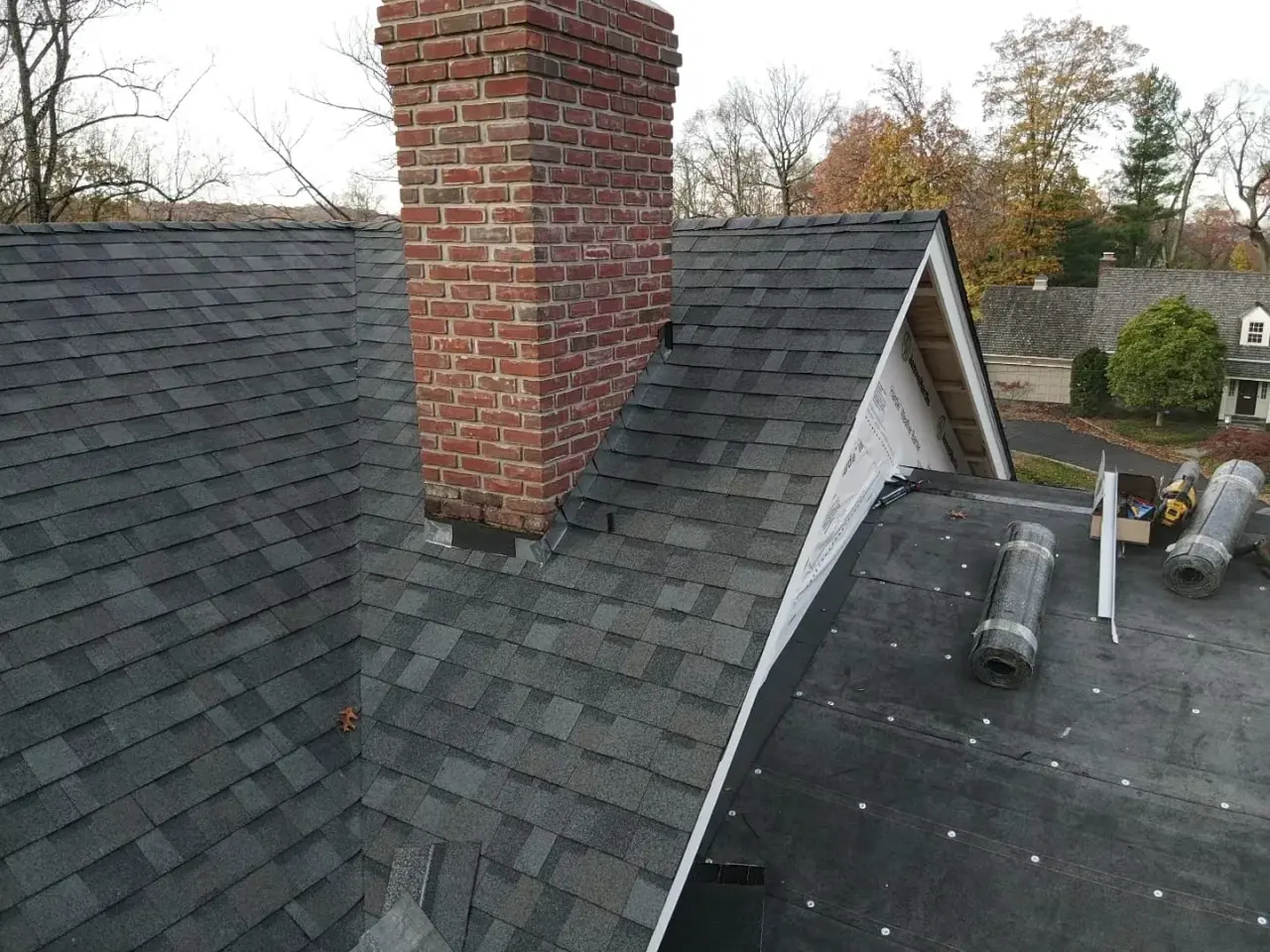 New step and counter flashing where a brick chimney meets a freshly shingled roof