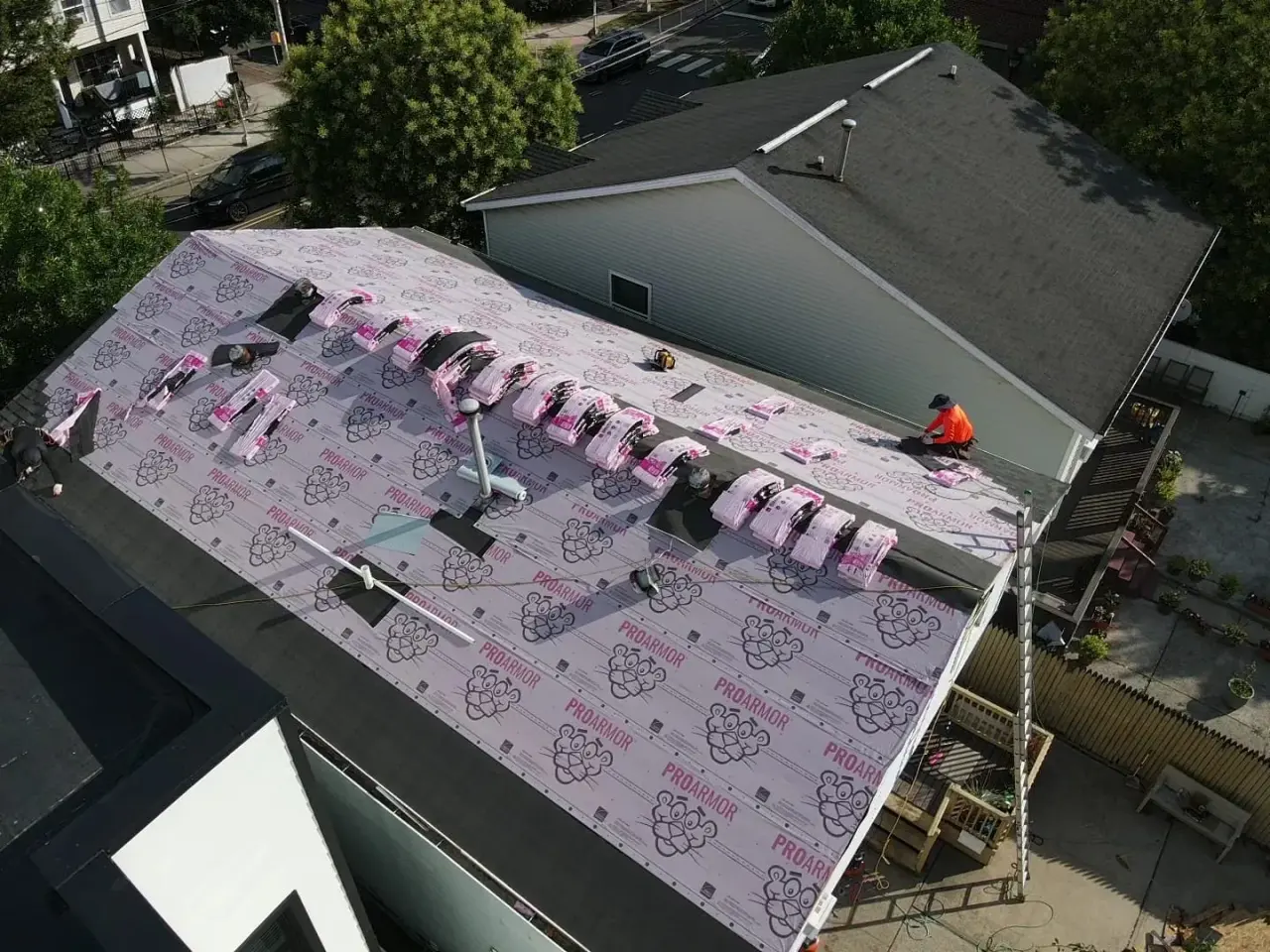 Shingle bundles staged along the ridge over new synthetic underlayment during a roof replacement