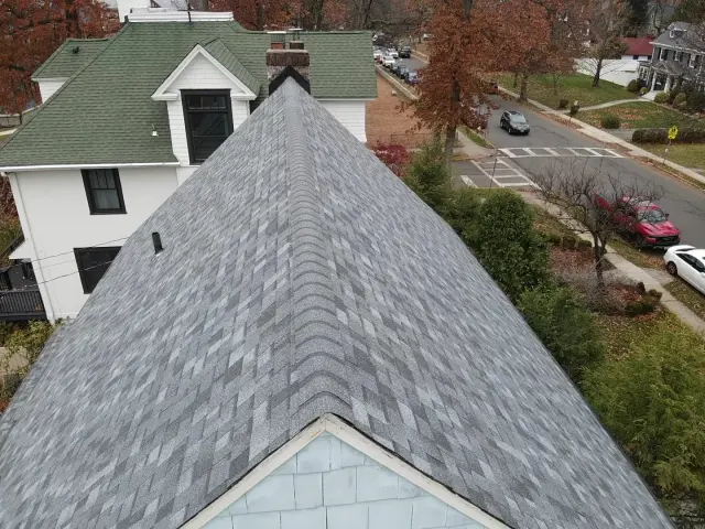 Finished gray architectural shingle roof with new ridge cap on a two-story home