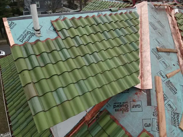 Green clay tile roof with a self-adhering leak barrier and copper valley metal underneath