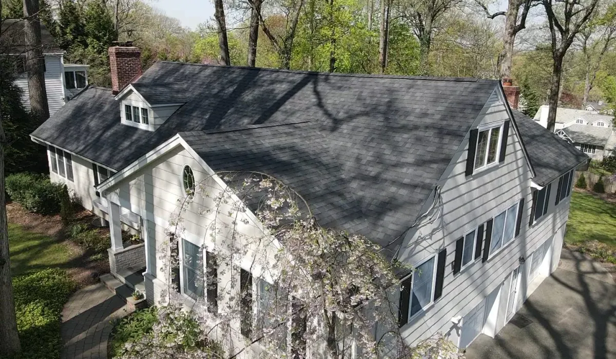 A New Jersey roofer inspecting damaged shingles and flashing while preparing a written repair estimate