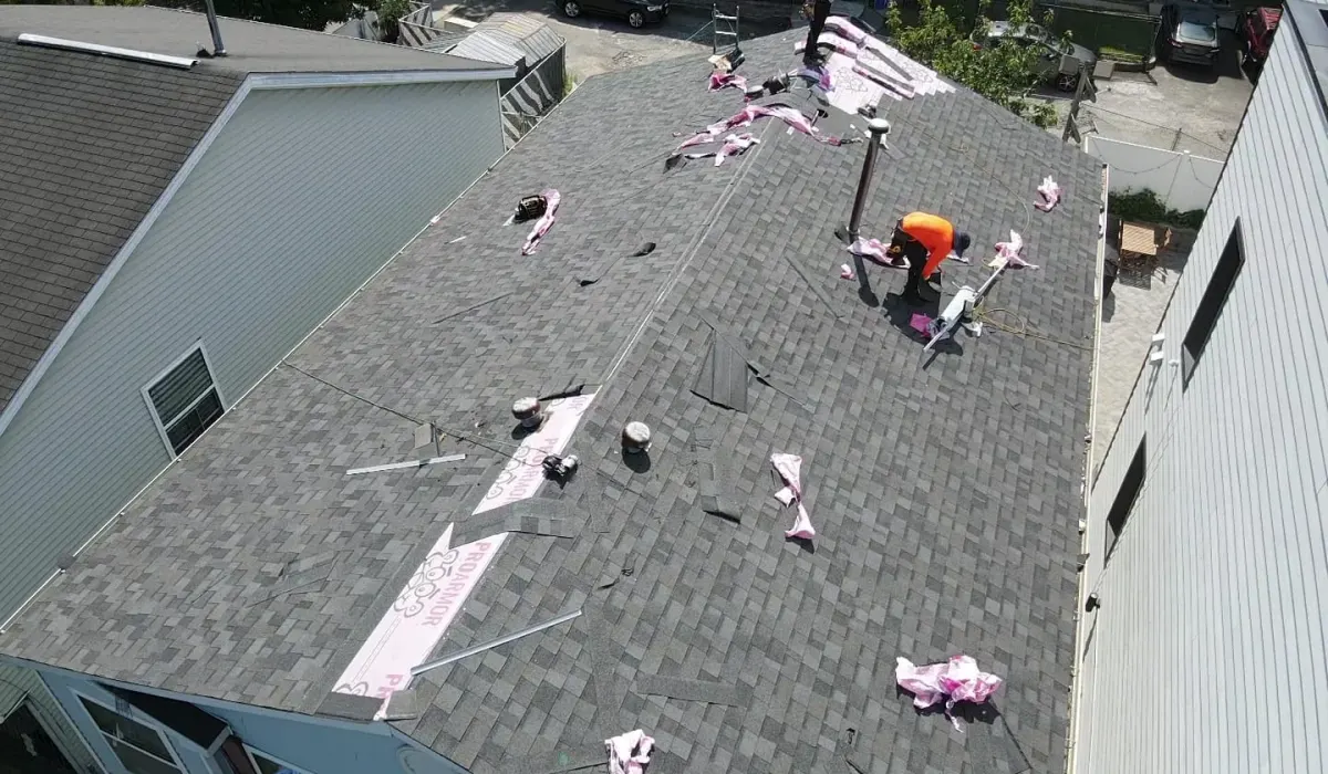 Wind-lifted asphalt shingles and exposed ridge cap on a New Jersey roof after a nor'easter