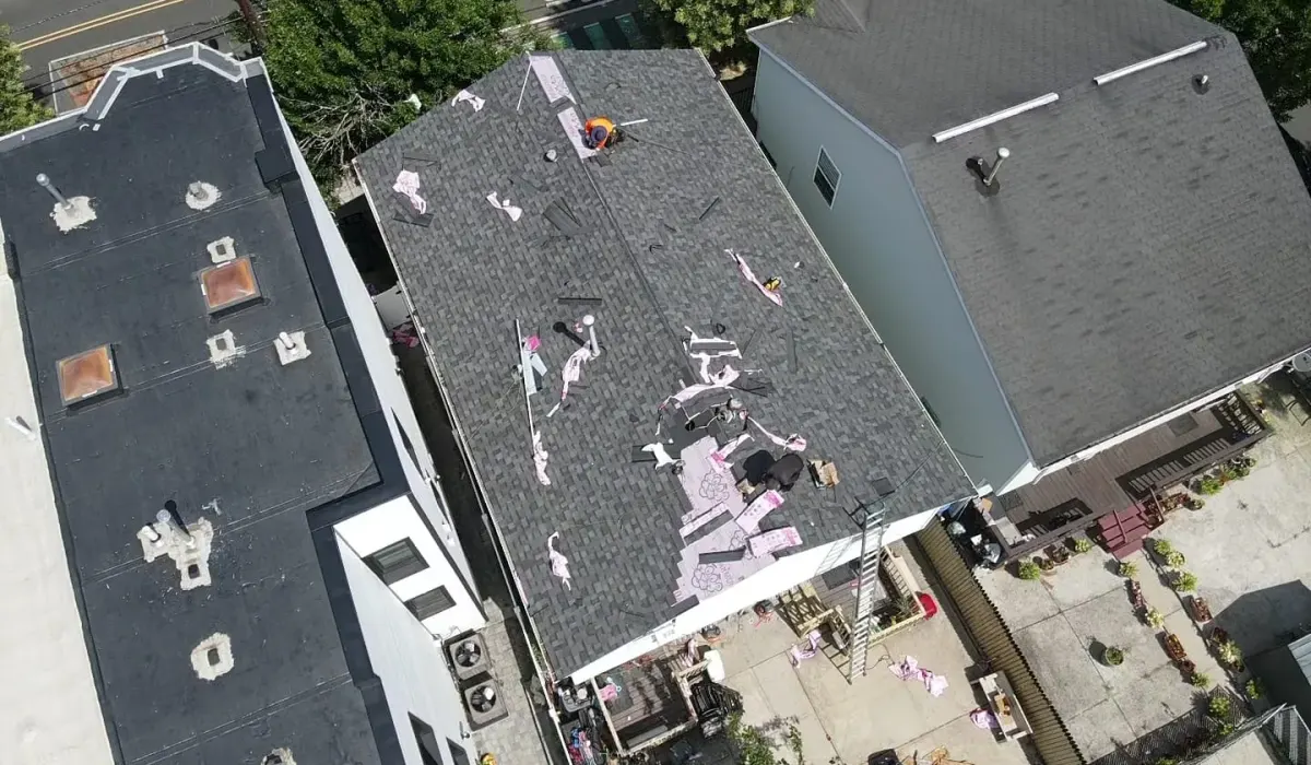 Damaged asphalt shingles being stripped from a New Jersey roof and documented before an insurance repair