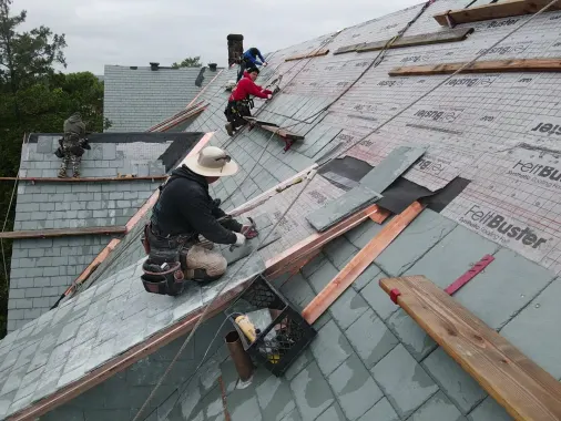 Roofer replacing slate on a steep roof with a slate ripper and wood cleats