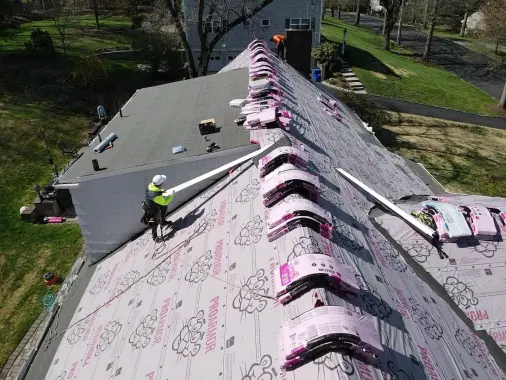 Shingle bundles staged along the ridge over new synthetic underlayment
